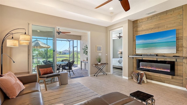 7525 Alumni Trl, Sarasota, FL 34243 - living area with ceiling fan, tile patterned flooring, a glass covered fireplace, a raised ceiling, and wooden walls