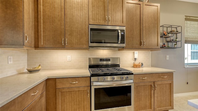 kitchen featuring light tile patterned floors, backsplash, and stainless steel appliances