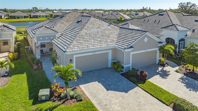 view of front of property featuring a front lawn, a garage, and a water view