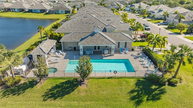 view of swimming pool featuring a water view, a yard, and a patio