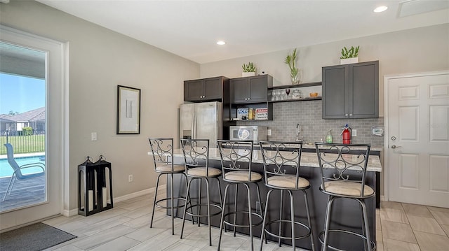 kitchen featuring appliances with stainless steel finishes, a kitchen island, decorative backsplash, and a kitchen bar