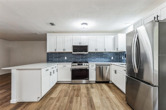 kitchen featuring light hardwood / wood-style floors, appliances with stainless steel finishes, tasteful backsplash, white cabinetry, and kitchen peninsula