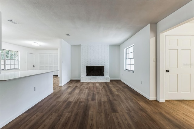 unfurnished living room with a fireplace, plenty of natural light, and dark hardwood / wood-style flooring