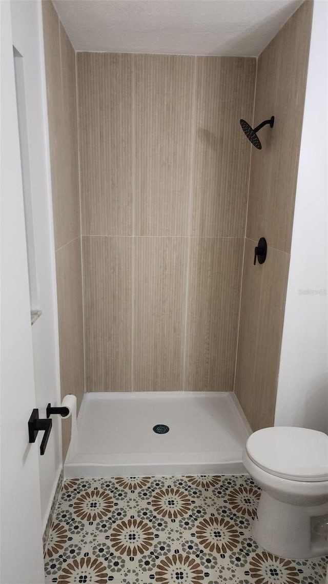 bathroom with a shower, toilet, and tile patterned flooring