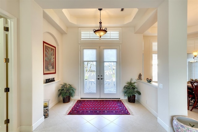 foyer entrance featuring a raised ceiling, light tile patterned floors, and french doors