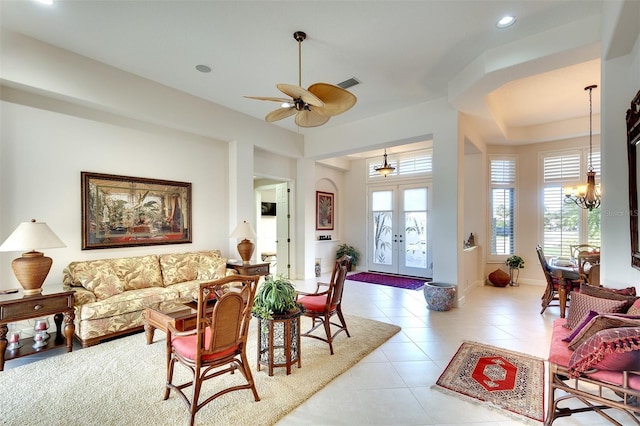 living room with french doors, light tile patterned floors, and ceiling fan with notable chandelier