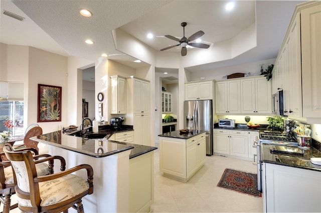 kitchen with kitchen peninsula, a textured ceiling, stainless steel appliances, sink, and a center island