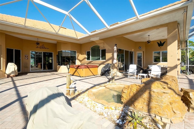 rear view of property featuring ceiling fan, a lanai, a patio, and a hot tub