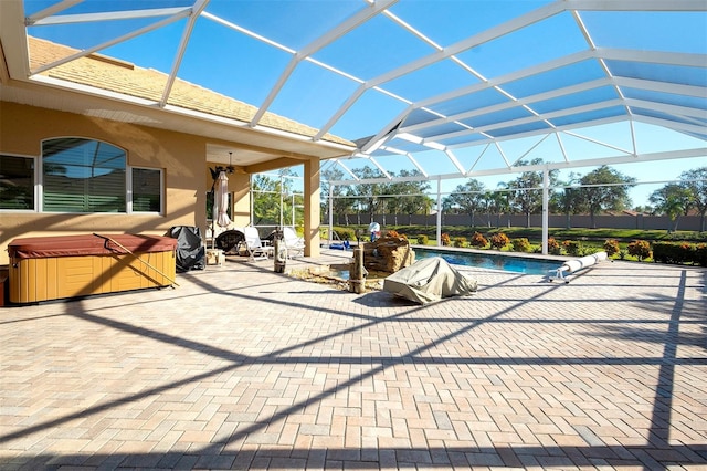 view of patio featuring glass enclosure and a swimming pool with hot tub