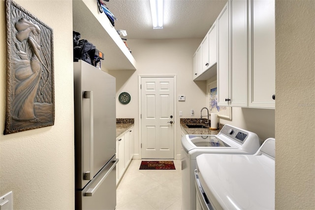 laundry area featuring washer and clothes dryer, sink, cabinets, and a textured ceiling