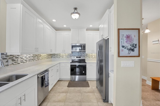 kitchen featuring white cabinetry, sink, stainless steel appliances, tasteful backsplash, and light tile patterned flooring