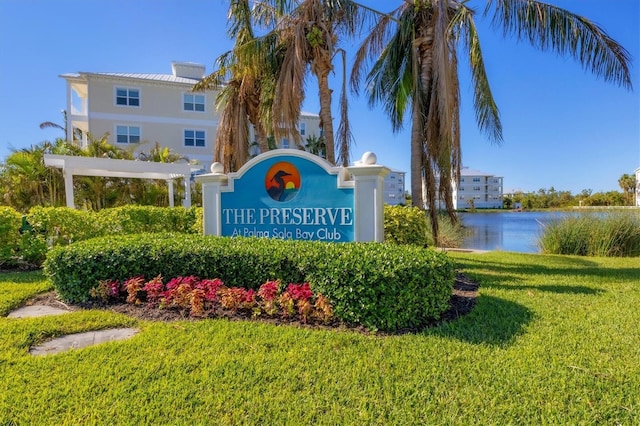 community / neighborhood sign with a lawn and a water view