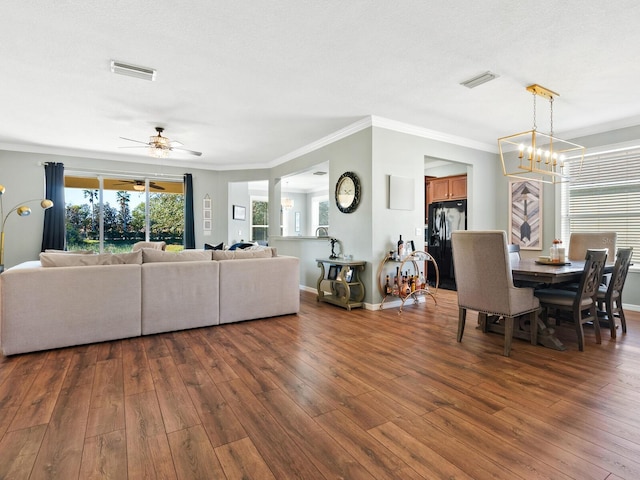 living room featuring a textured ceiling, dark hardwood / wood-style floors, ornamental molding, and ceiling fan with notable chandelier