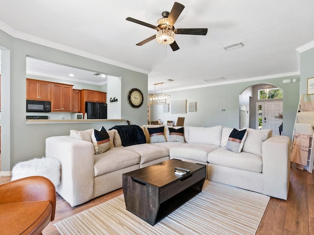 living room with ceiling fan with notable chandelier, light hardwood / wood-style floors, and ornamental molding