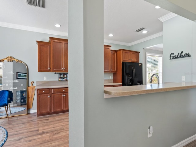 kitchen featuring sink, ornamental molding, light hardwood / wood-style floors, black fridge with ice dispenser, and kitchen peninsula