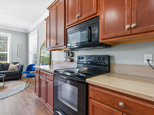 kitchen with a healthy amount of sunlight, crown molding, black appliances, and light wood-type flooring