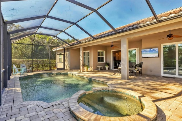 view of swimming pool with glass enclosure, ceiling fan, a patio, and an in ground hot tub