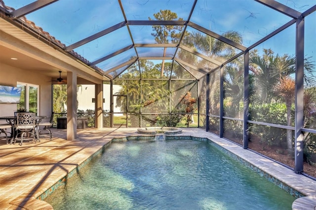 view of pool featuring glass enclosure, an in ground hot tub, ceiling fan, and a patio