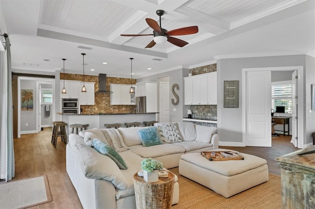 living room with light wood-type flooring, crown molding, ceiling fan, and coffered ceiling