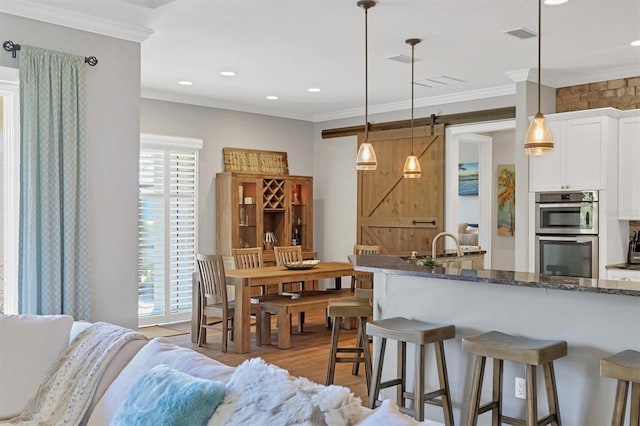 kitchen featuring white cabinets, crown molding, dark stone countertops, and hanging light fixtures