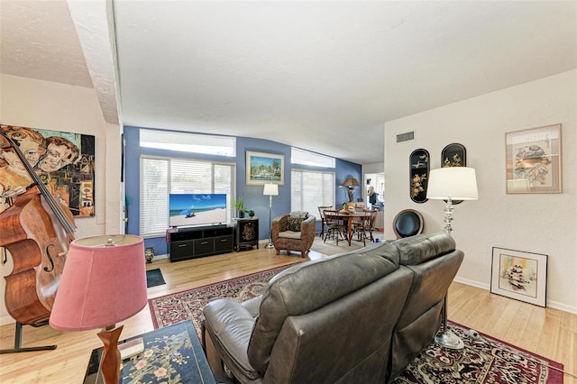 living room with light hardwood / wood-style floors and vaulted ceiling