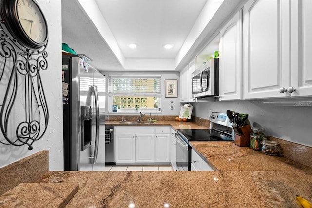 kitchen with dark stone counters, sink, light tile patterned floors, white cabinetry, and stainless steel appliances