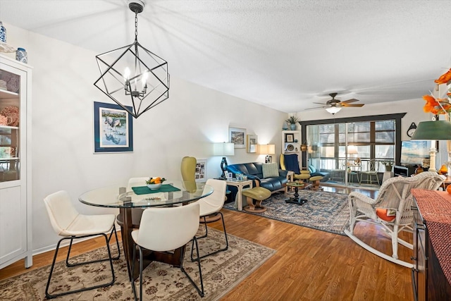 dining room with hardwood / wood-style floors, ceiling fan with notable chandelier, and a textured ceiling