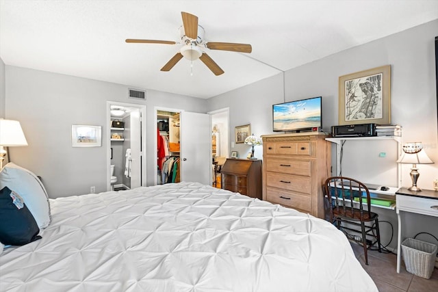 bedroom with ensuite bathroom, ceiling fan, light tile patterned floors, a spacious closet, and a closet