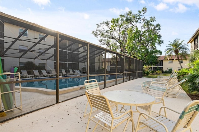 view of patio with glass enclosure and a community pool