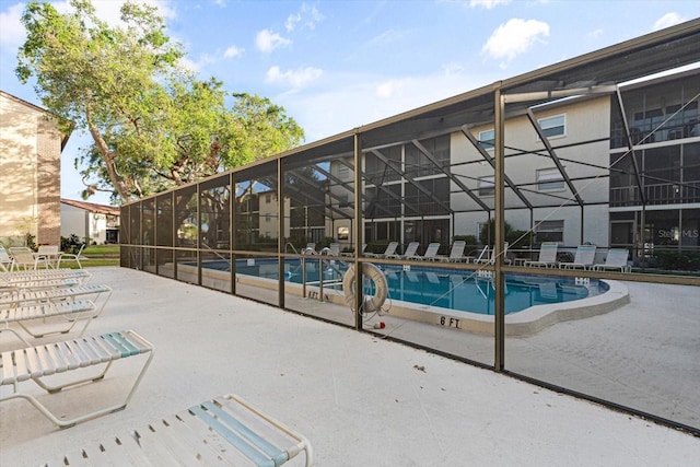 view of swimming pool with glass enclosure and a patio area