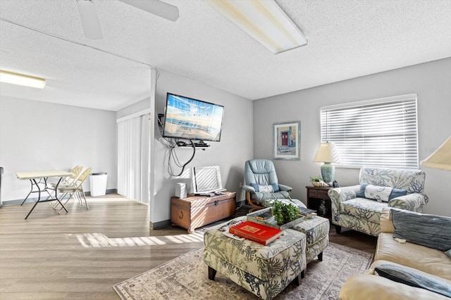 living room featuring ceiling fan, hardwood / wood-style floors, and a textured ceiling