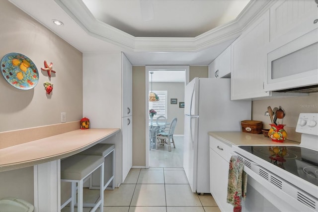 kitchen featuring white appliances, white cabinets, crown molding, light tile patterned floors, and a tray ceiling