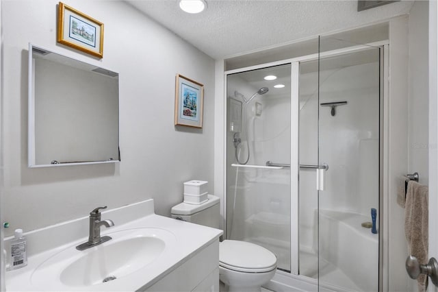 bathroom with vanity, a textured ceiling, toilet, and a shower with shower door