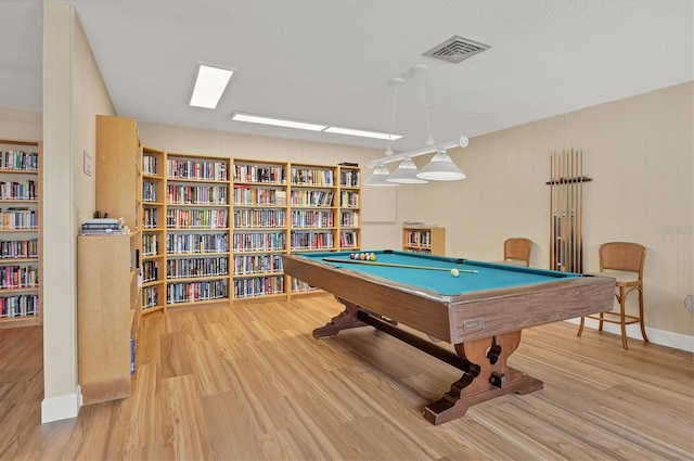 game room featuring a textured ceiling, light hardwood / wood-style flooring, wood walls, and billiards