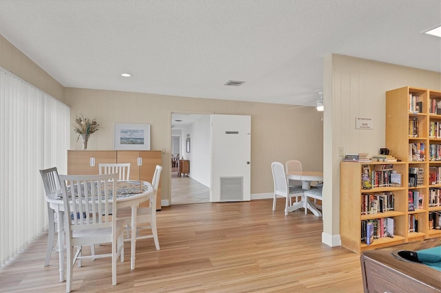 dining room featuring a textured ceiling, light hardwood / wood-style floors, and ceiling fan