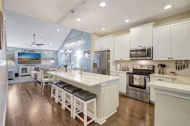 kitchen with sink, pendant lighting, lofted ceiling, white cabinets, and appliances with stainless steel finishes