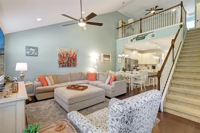 living room with high vaulted ceiling, dark hardwood / wood-style floors, and ceiling fan with notable chandelier