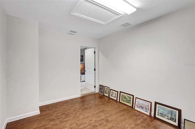 unfurnished room featuring hardwood / wood-style floors and a textured ceiling