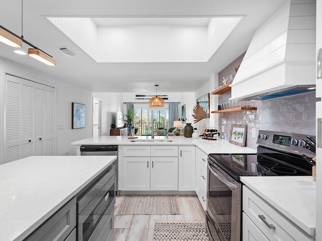 kitchen with pendant lighting, stainless steel range with electric cooktop, white cabinets, sink, and light hardwood / wood-style flooring