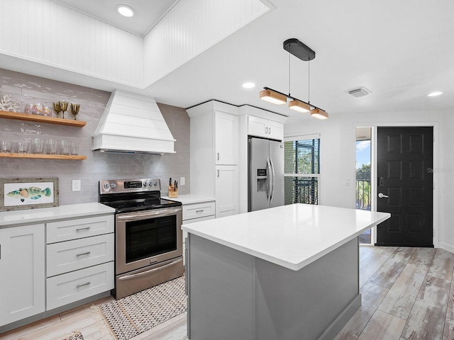 kitchen featuring decorative light fixtures, decorative backsplash, appliances with stainless steel finishes, custom exhaust hood, and light wood-type flooring