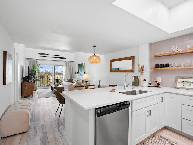 kitchen with white cabinetry, sink, light hardwood / wood-style flooring, stainless steel dishwasher, and decorative light fixtures