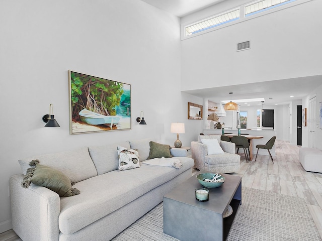 living room with light wood-type flooring and a high ceiling