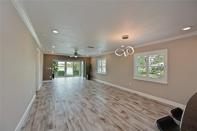 unfurnished living room featuring ceiling fan with notable chandelier, light wood-type flooring, a textured ceiling, and ornamental molding