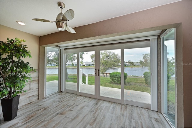 doorway with a wealth of natural light, light hardwood / wood-style flooring, and a water view