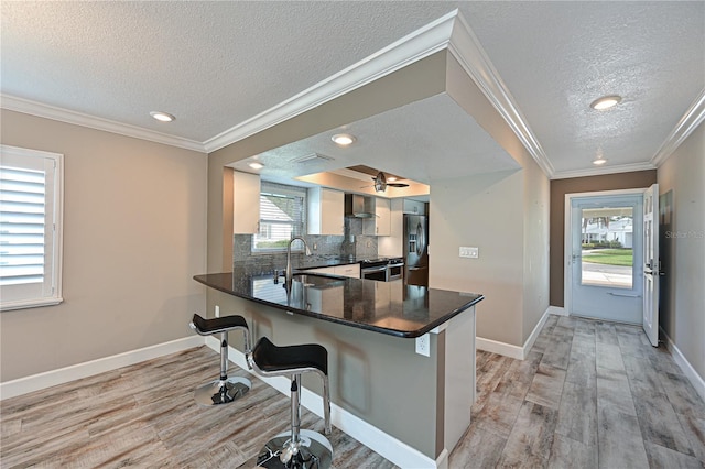 kitchen with sink, light hardwood / wood-style flooring, kitchen peninsula, a textured ceiling, and a kitchen bar