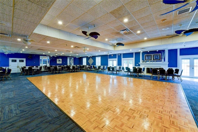 workout area with a drop ceiling and parquet flooring