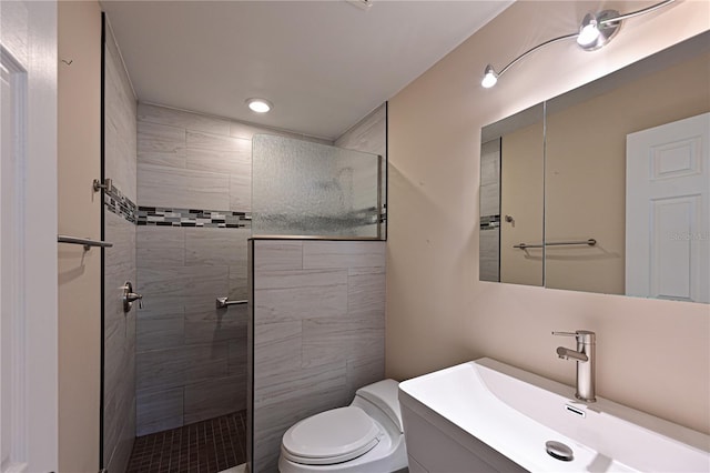 bathroom featuring a tile shower, vanity, and toilet