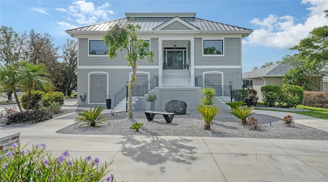 coastal inspired home featuring french doors, metal roof, concrete driveway, and a standing seam roof