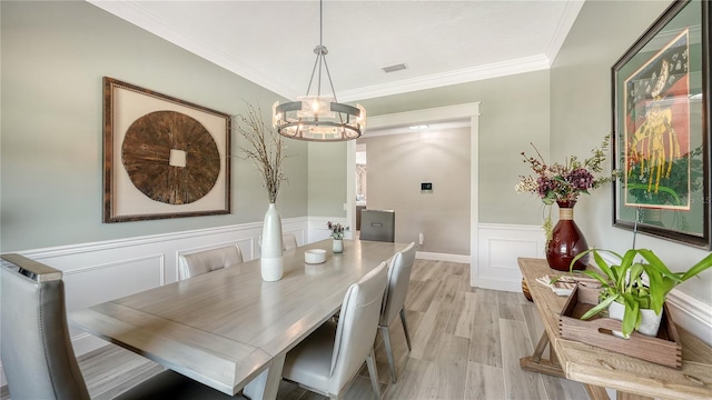 dining room featuring crown molding, light hardwood / wood-style flooring, and a chandelier