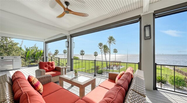 sunroom / solarium featuring a water view, a ceiling fan, and a healthy amount of sunlight